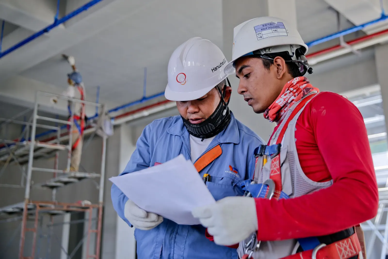 Dos jefes de obra revisando los planos en el andamio